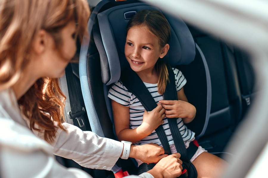 Verkehrssicherheit - Mutter setzt ihre Tochter in einen Autositz - kleiner