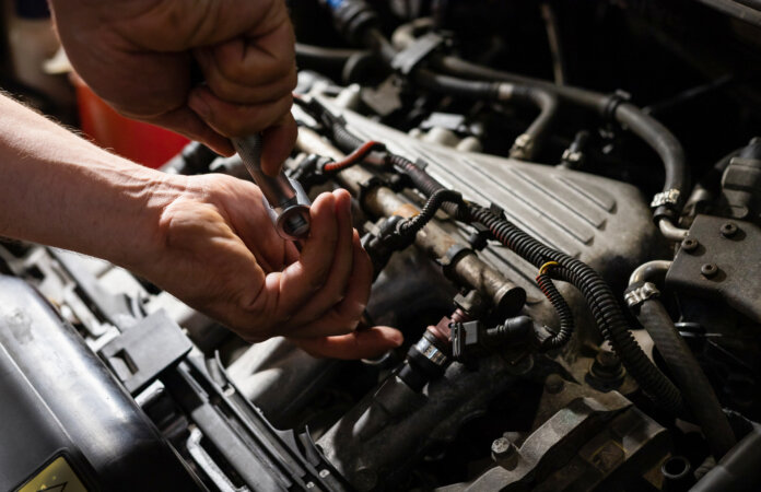 Automechaniker schraubt etwas im Autoinnenraum